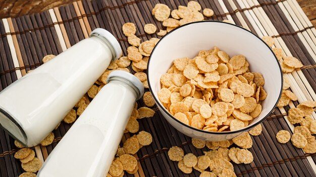 Gesunde Cornflakes und Milch auf einer Bambusserviette. Glasflasche mit Milch für ein gesundes Frühstück