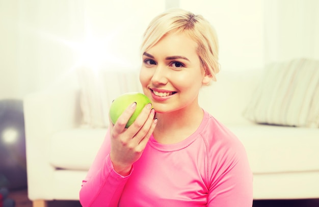 Gesunde Ernährung, Bio-Lebensmittel, Ernährung und People-Konzept - glückliche Frau, die zu Hause Apfel isst