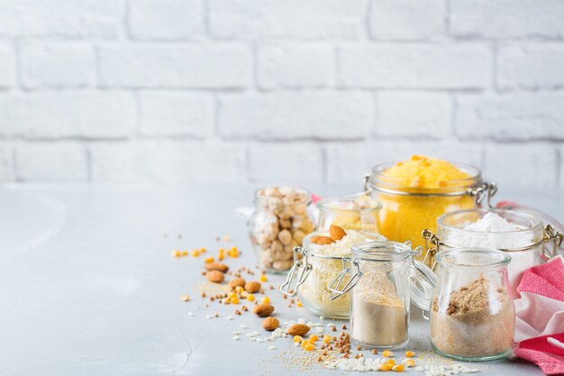 Gesunde Ernährung, Diät, ausgewogenes Lebensmittelkonzept. Auswahl an glutenfreien Lebensmitteln und Mehl, Mandeln, Mais, Reis auf einem Holztisch. Raumhintergrund kopieren