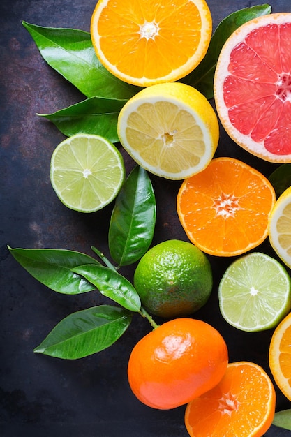 Gesunde Ernährung Ernährung Naturkonzept Zitrusfrüchte Vitamin Hintergrund Orange Grapefruit Mandarine Limette Zitrone mit Blättern auf einem schwarzen Grunge-Tisch Draufsicht flach lag Overhead