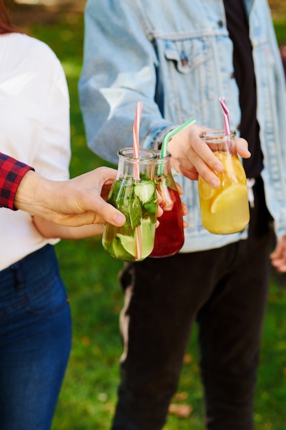 Gesunde Ernährung. Freunde trinken frischen Saft Detox auf grünem Naturhintergrund