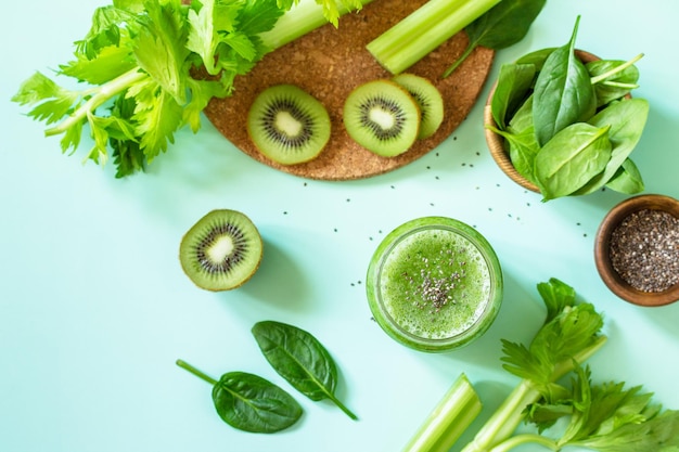 Gesunde Ernährung Grüner Smoothie mit Sellerie-Kiwi und Spinat auf grünem Hintergrund Draufsicht flach gelegt