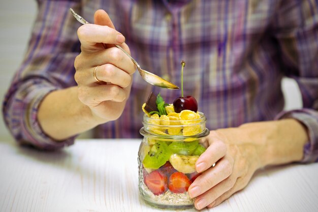 Gesunde Ernährung. Mädchenhand mit einem Löffel und Haferflocken mit Beeren und Früchten, Messer. Food-Fotografie