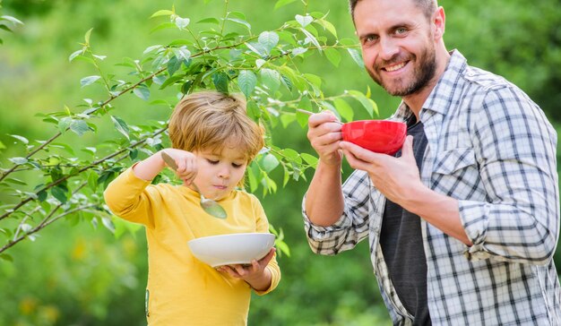 Gesunde Ernährung und Diät. Milchprodukte. Alles gute zum Vatertag. Kleiner Junge mit Papa isst Müsli. sohn und vater essen im freien. Familienbande. Gemeinsame Zeit genießen. Verliebt in gesundes Essen. Morgen.