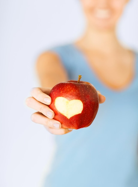 Gesunde ernährung und lebensweise - frauenhand, die roten apfel mit herzform hält