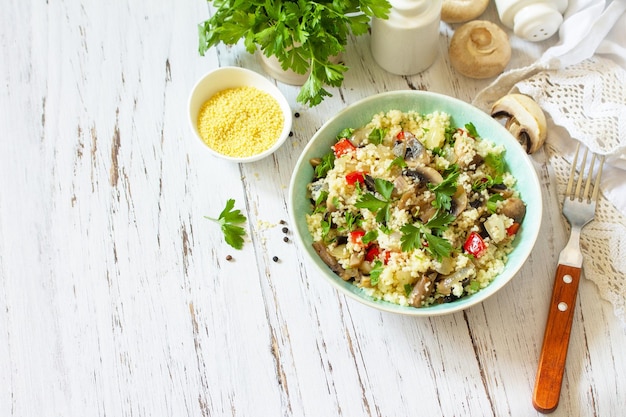 Gesunde Ernährung Veganer Salat mit Couscous und Champignons auf einem Küchentisch aus Holz Platz kopieren