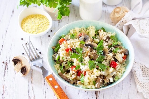 Gesunde Ernährung Veganer Salat mit Couscous und Champignons auf einem Küchentisch aus Holz