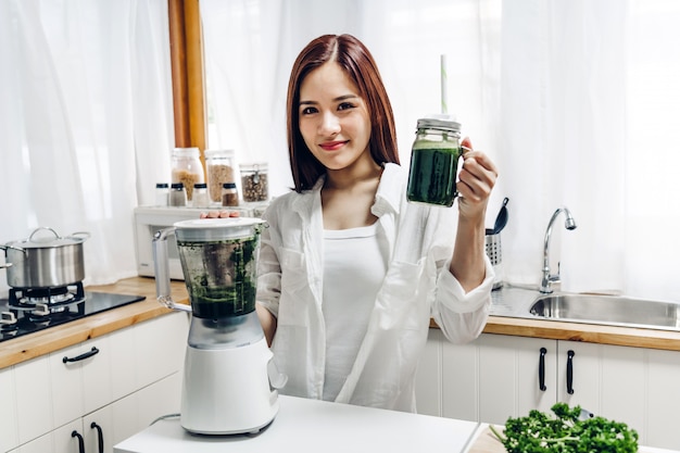 Gesunde Frau genießen, grünes Gemüse Detox Smoothie zu machen