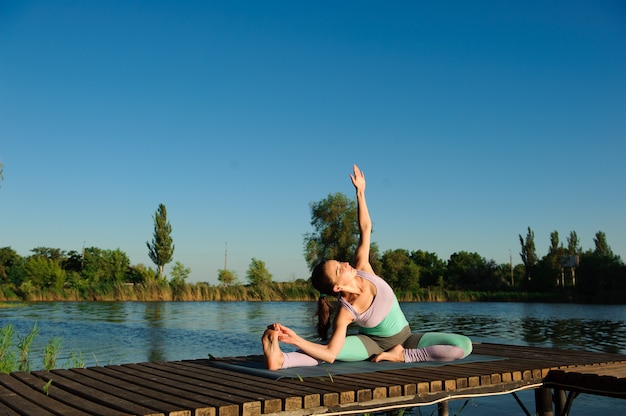 Gesunde Frau Lebensstil ausgewogen praktizieren Meditieren und Energie Yoga auf der Brücke am Morgen die Natur.