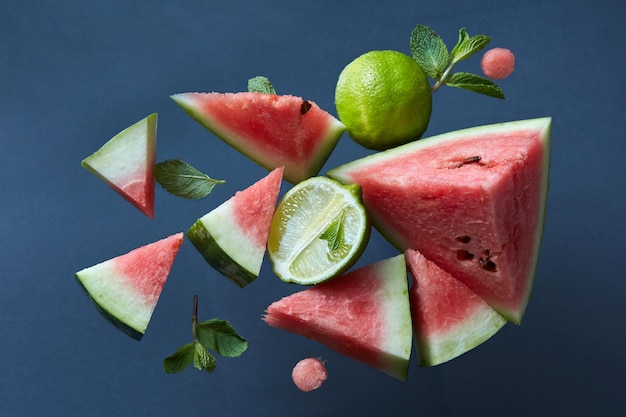 Gesunde frische Wassermelonenstücke mit Minze und Limette auf schwarzer Oberfläche