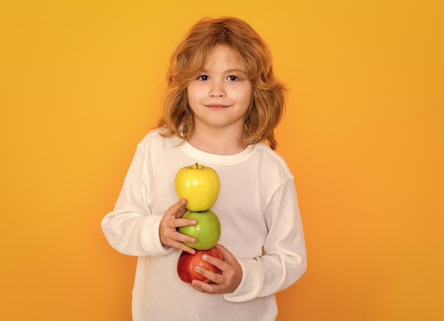 Gesunde Früchte für Kinder Kind mit Apfel im Studio Studioportrait von niedlichen Kind halten Apfel isoliert auf gelbem Hintergrund