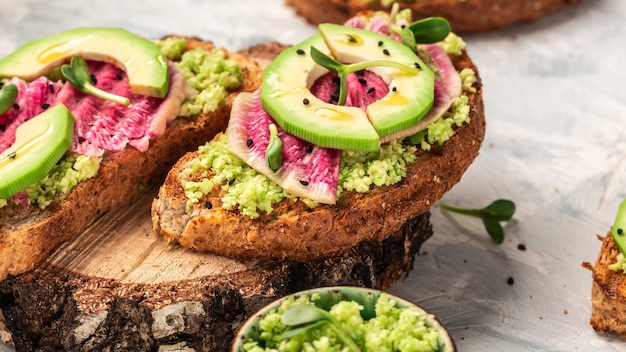 Gesunde Frühstückstoasts aus geschnittenem Wassermelonen-Rettich oder chinesischem Daikon und Avocado auf hellem Hintergrund Draufsicht Lebensmittelrezepthintergrund Nahaufnahme