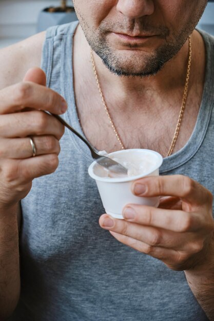 Gesunde Frühstücksvielfalt Joghurt mit Obst und Samen Mann isst Joghurt am Tisch in der Küche Nahaufnahme eines unerkennbaren Mannes