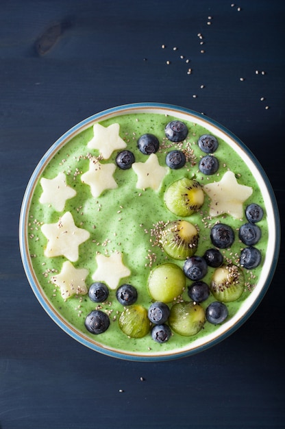 Gesunde grüne Spinat-Smoothie-Schüssel mit Blaubeeren, Apfelsternen, Kiwi, Chiasamen