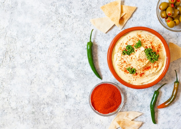 Gesunde hausgemachte Hummus serviert mit Paprikapulver, Fladenbrot, Oliven und Petersilie. Nahöstliche Küche, israelische Küche, levanesische Küche, levantinische Küche.