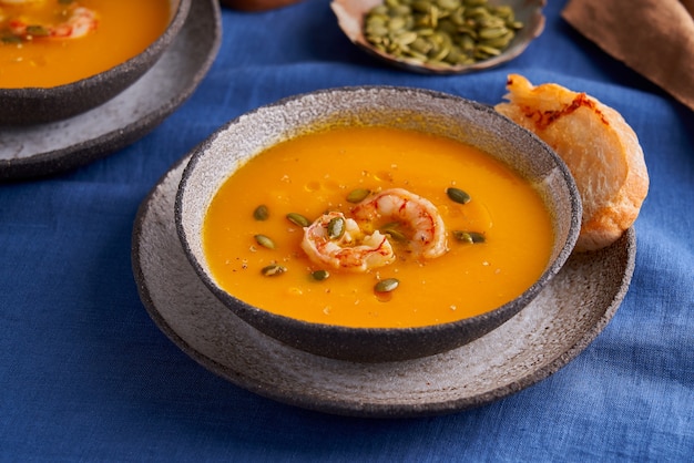 Gesunde herbstliche Kürbis-Karotten-Sahne-Püree-Suppe mit Garnelenkräutern und Ciabatta-Toast