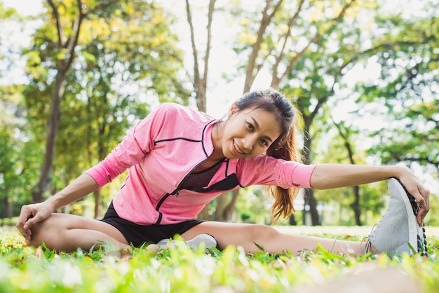 Gesunde junge asiatische Frau, die am Park trainiert. Geeignete junge Frau, die Trainingstraining am Morgen tut