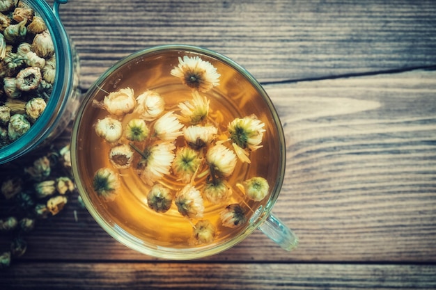 Gesunde Kamillenteetasse und Glasgefäß mit trockenen Gänseblümchen Draufsicht