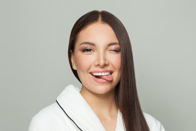 Gesunde Modelfrau zeigt Zunge auf weißem Hintergrund Lustige Gesichtsporträt