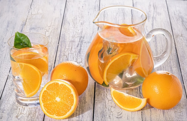 Gesunde Orangenentgiftung mit frischer Orange und Limette, in Glas auf Holzwand.