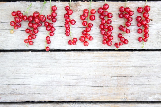 Gesunde rote Johannisbeeren auf einem hölzernen Hintergrund im Gartensommerkonzept