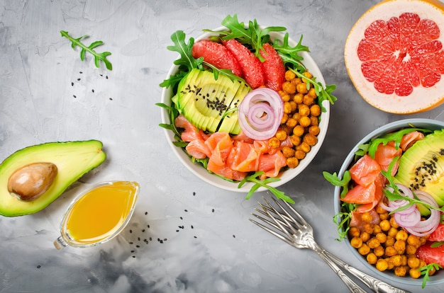 Gesunde Salatschüssel mit Lachs, Grapefruit, würzigen Kichererbsen, Avocado, roten Zwiebeln und Rucola