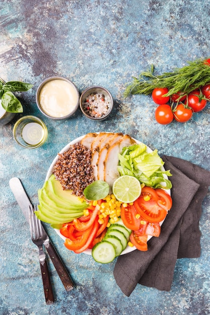 Gesunde Salatschüssel mit Quinoa, Tomatentruthahn, Avocado, Paprika, Mais, Limette und gemischtem Grün, Draufsicht. Gesunde Lebensmittelkonzeption. Superfood-Mahlzeit.