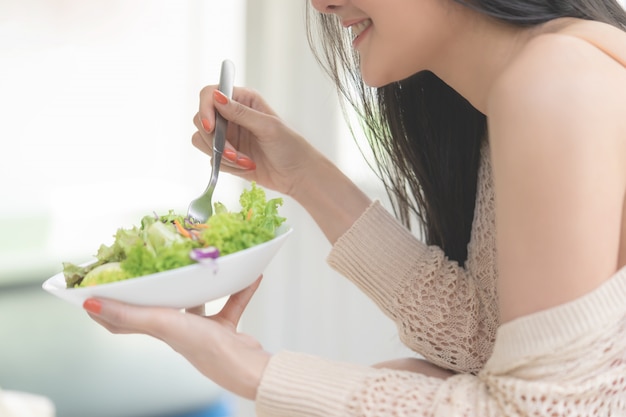 Gesunde sexy junge Frau isst grünen Salat für gesundes Lebensstillebensmittelkonzept