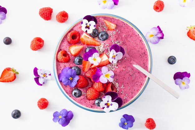 Gesunde Sommerbeeren-Smoothie-Schüssel mit Blumen und Chiasamen