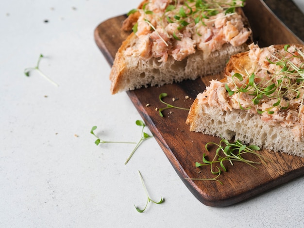 Gesunde Toasts mit Lachspastete und frischen grünen Sprossen auf hefefreiem Brot auf Holzschneidebrett