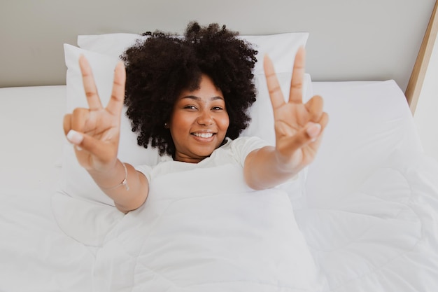 Gesunde und fröhliche Afroamerikanerin im Bett Guten Morgen, wach gut gelaunt auf.