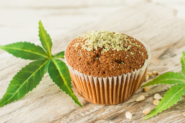 Gesunde und leckere vegane und glutenfreie Muffins in Folge mit Hanfsamen auf einem Marmortisch. Marihuana-Cupcake-Muffins mit Cannabisblättern.