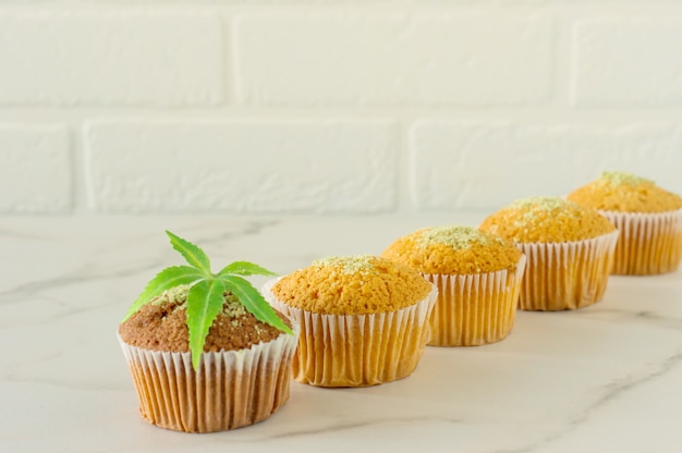 Gesunde und leckere vegane und glutenfreie Muffins in Folge mit Hanfsamen auf einem Marmortisch. Marihuana-Cupcake-Muffins mit Cannabisblättern.