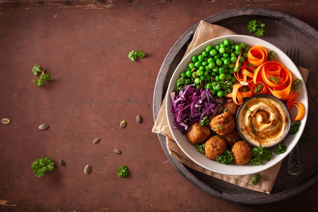 Gesunde vegane Lunch Bowl mit Falafel Hummus Karottenbändern Kohl und Erbsen