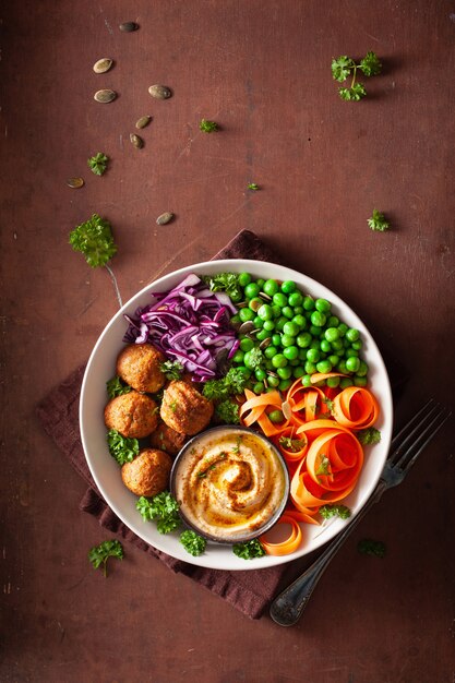 Gesunde vegane Lunch Bowl mit Falafel Hummus Karottenbändern Kohl und Erbsen