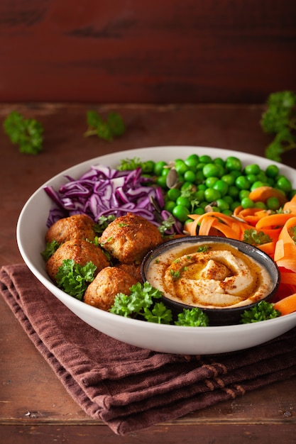 Gesunde vegane Lunch Bowl mit Falafel Hummus Karottenbändern Kohl und Erbsen