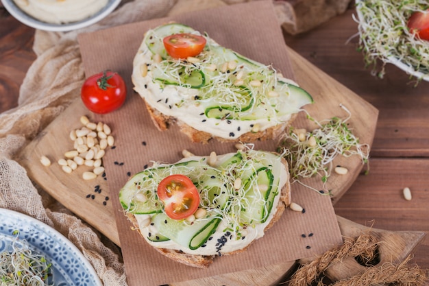 Gesunde vegetarische Bruschettas mit Brot, Hummus, Kirschtomaten, Gurken und Pinienkernen