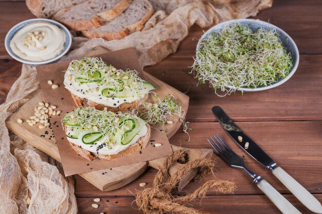 Gesunde vegetarische Bruschettas mit Brot, Mikrogrün, Hummus, Gurken und Pinienkernen