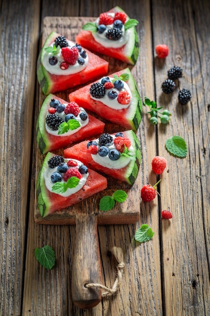 Gesunde Wassermelonenpizza mit Beerenschlagsahne und Minzblättern