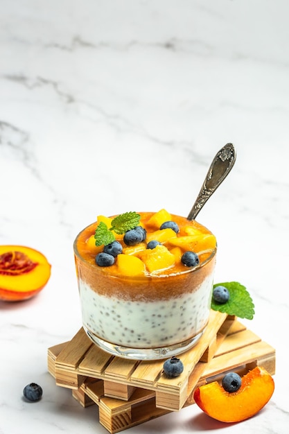 Gesunder Chia-Pudding mit Joghurt und Obst Pfirsich und Heidelbeere Hausgemachtes Dessert mit Obstplatz für Text-Draufsicht