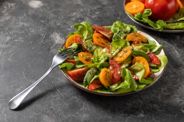 Gesunder Gemüsesalat aus frischem Gemüse von Tomaten, Gurken, Zwiebeln, Spinat, Salat auf einem Teller. Diätmenü. Von oben betrachten.