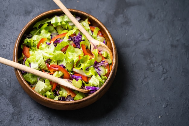 Gesunder Gemüsesalat aus frischen Tomaten, Gurken, Zwiebeln, Spinat, Salat und Sesam auf Teller.