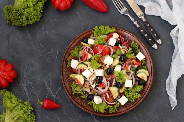 Gesunder griechischer Salat aus Salat, Tomate, Käse auf einem Teller auf dunklem Hintergrund