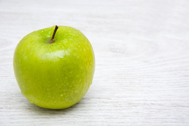 Gesunder grüner Apfel auf weißem Holztisch