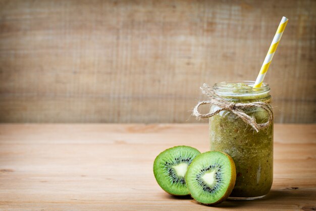 Gesunder grüner Smoothie in einem Glas auf altem Holz.