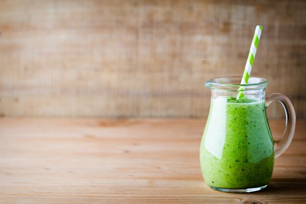 Gesunder grüner Smoothie in einem Glas auf altem Holz.