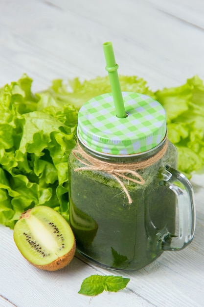 Foto gesunder grüner smoothie mit bestandteilen auf weißem hölzernem hintergrund
