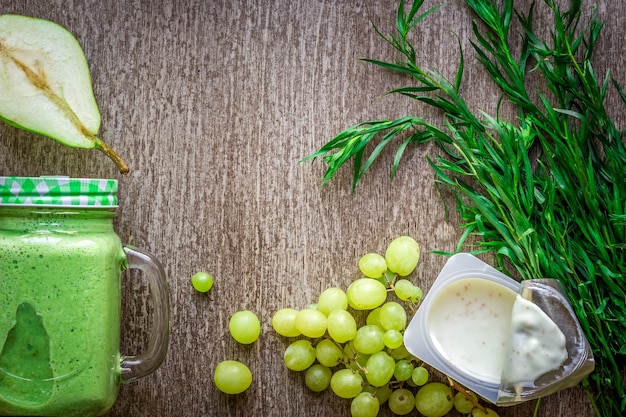 Gesunder grüner Smoothie mit Spinat in einer Tasse gegen auf hölzernem Hintergrund