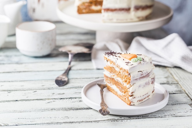 Gesunder hausgemachter Karottenkuchen mit Frischkäse-Zuckerguss auf weißem Holztisch