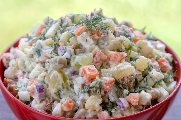 Gesunder hausgemachter russischer traditioneller Salat Olivier verzehrfertig, Nahaufnahme, Ansicht von oben